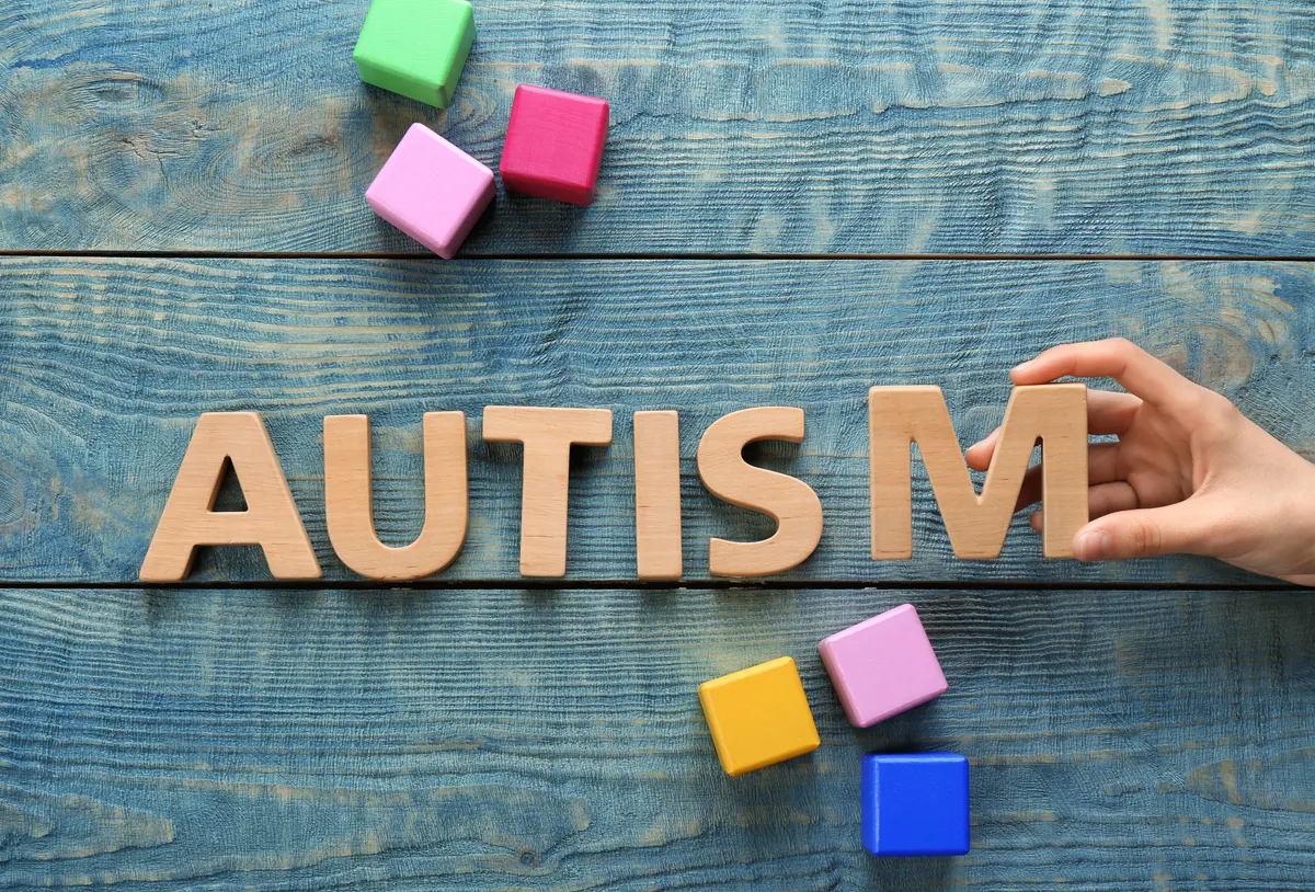 Colourful wooden blocks spelling AUTISM on a desk, representing accessible learning materials.