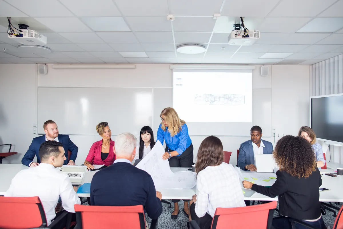 A facilitator leading a small, engaged training group around a table in natural light.
